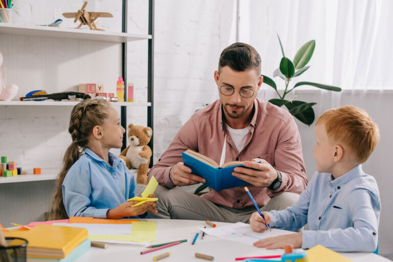 teacher-in-eyeglasses-reading-book-to-kids-at-tabl-2024-11-17-09-22-28-utc